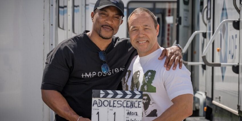 Actors Ashley Walters and Stephen Graham stand together, holding a clapperboard on the set of a new Netflix drama called Adolescence