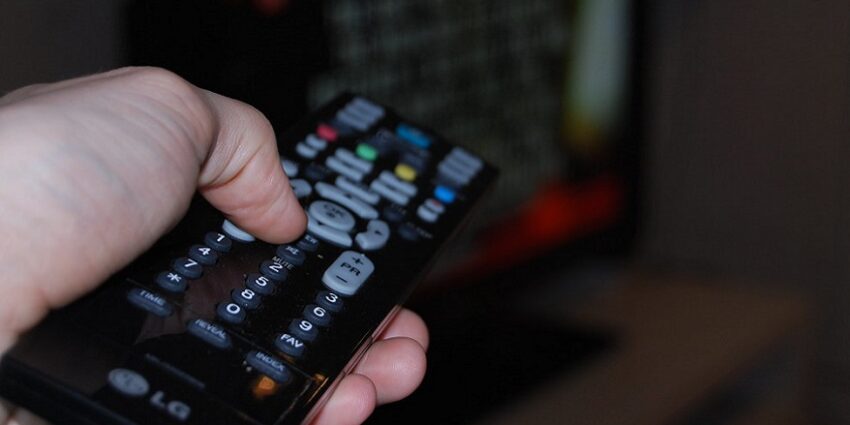 A hand seen holding a TV remote control