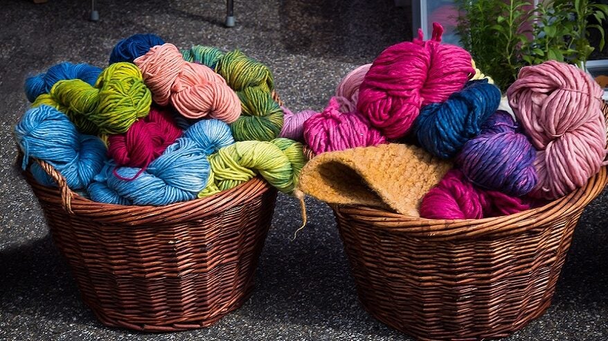 Very colourful balls of wool in two wicker baskets