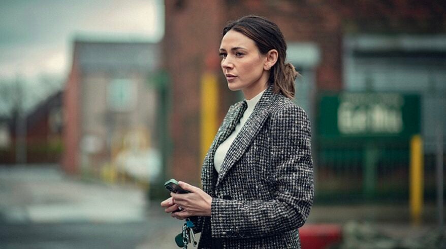 Actor Michelle Keegan in Fool Me Once, standing on a street wearing a grey jacket and holding keys