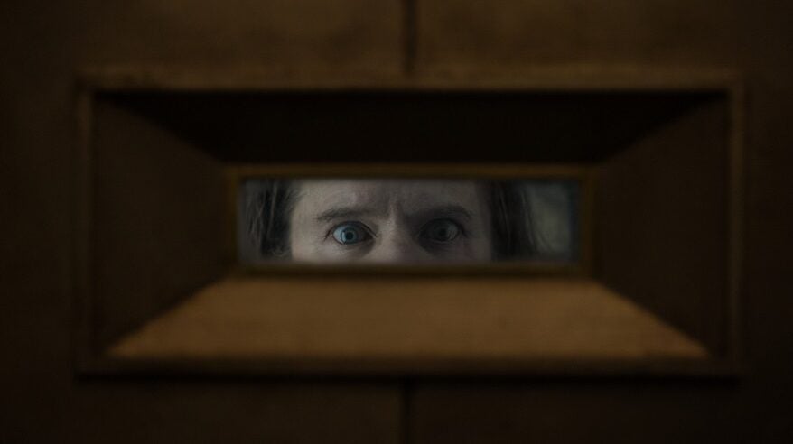 Eyes through a slot in a door, from drama Silo