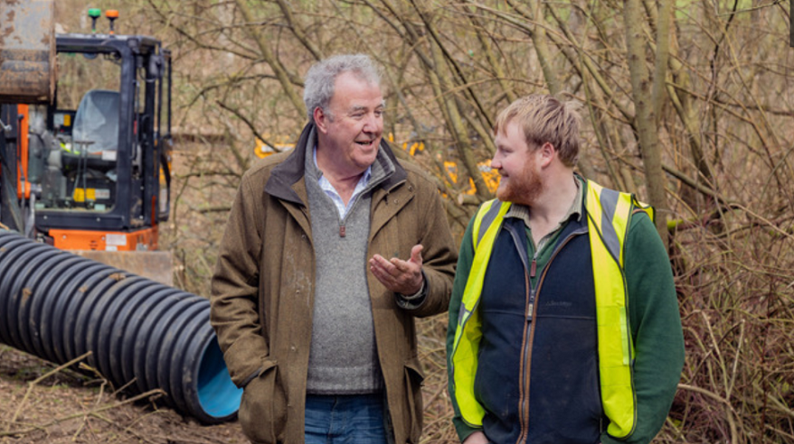 Jeremy Clarkson and Caleb Cooper stand in a field with trees behind them