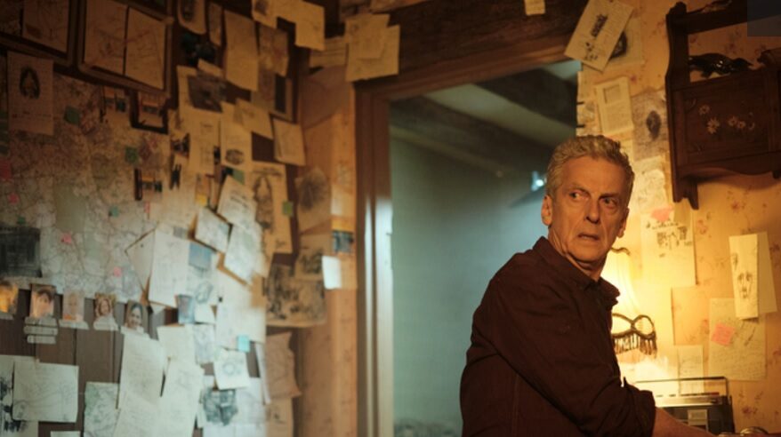 Peter Capaldi in The Devil's Hour, turning to look over his shoulder in a room with notes and papers on the walls