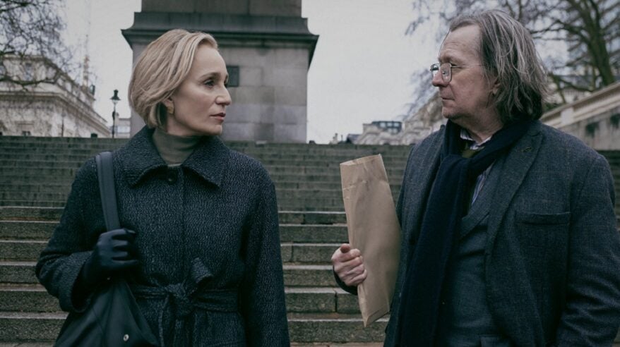 Kristin Scott Thomas and Gary Oldman in Slow Horses, standing in front of stone steps and a statue