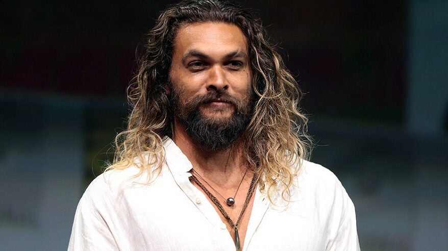 Actor Jason Momoa in an open-necked white top and necklaces