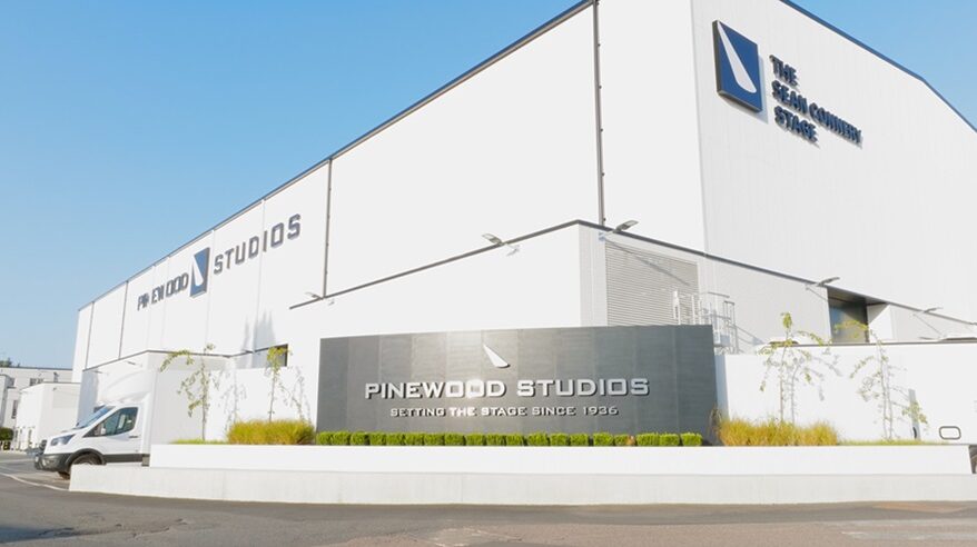 Exterior shot of Pinewood Studios with white building and branded plaque in front