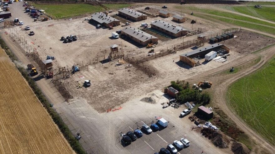 Aerial view of large patch of land with cars and aircraft hangars visible