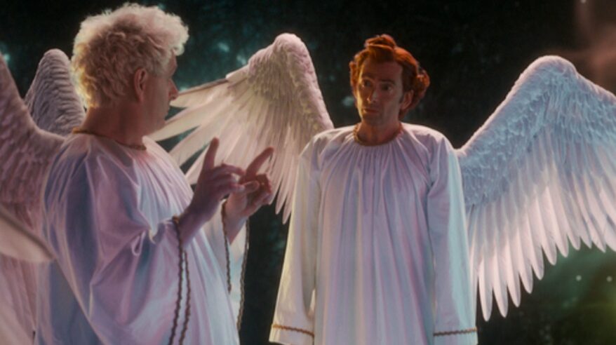 Actors Michael Sheen as angel Aziraphale, in costume with David Tennant as demon Crowley in Good Omens S2. Both dressed in white as angels with wings