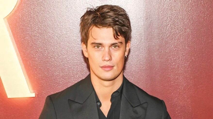 Head and shoulders shot front-on of actor Nicholas Galitzine in dark jacket and dark open-necked shirt