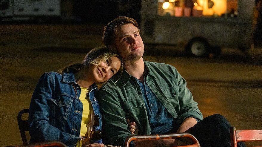 A man and a woman sit in adjacent chairs outside at night