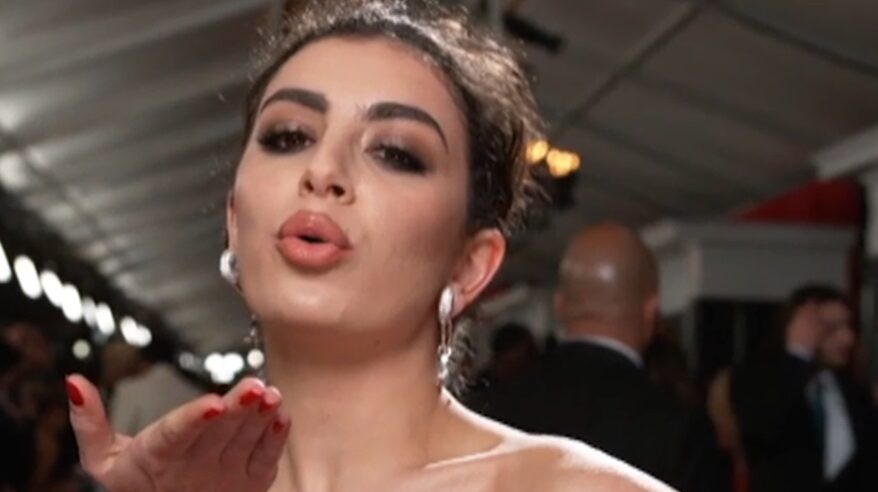 Singer Charli xcx with hair pulled back and blowing a kiss to camera