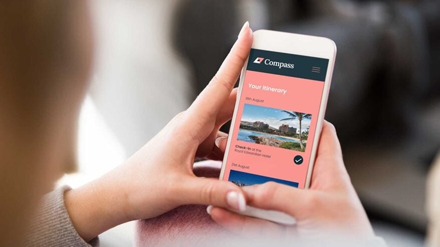 Two hands holding a smartphone with Compass Travel Management on the screen