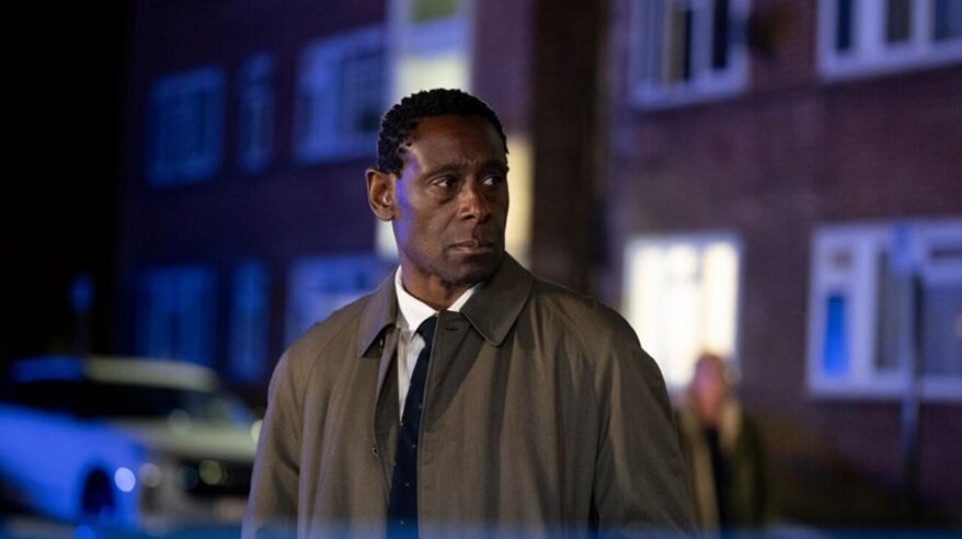 Actor David Harewood in C4 drama Pierre, in brown overcoat, shirt and tie, in dark street at night