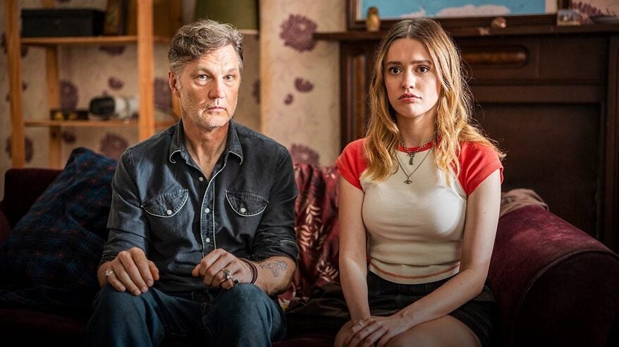 Two lead actors from BBC comedy Daddy Issues sit side by side on a sofa, looking outwards