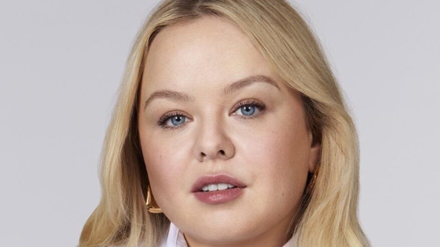 Colour headshot of actor Nicola Coughlan with blonde hair and gold earring visible above white collar