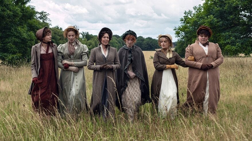 Female cast of Netflix's Pride and Prejudice in period costume walking across a field