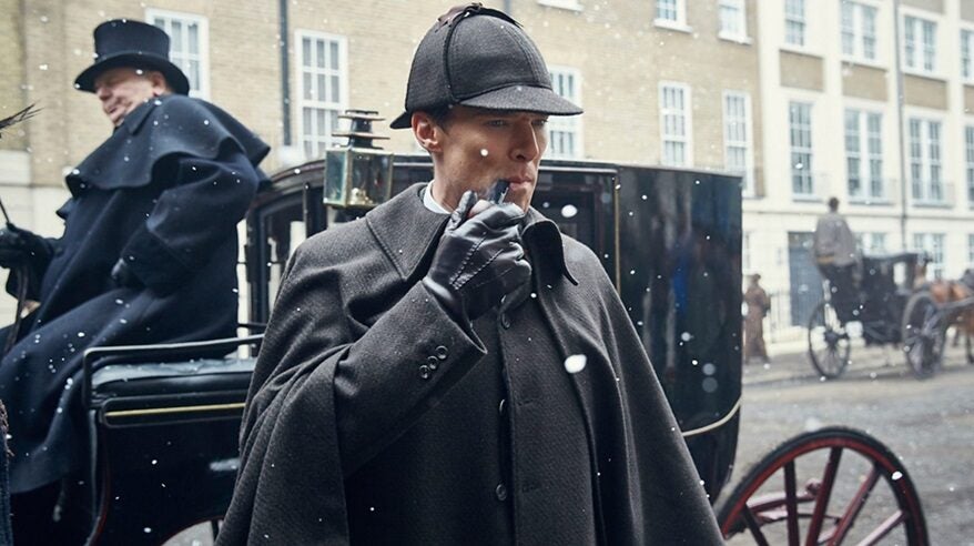 Actor Benedict Cumberbatch in costume as Sherlock Holmes, with deerstalker and pipe in front of a horse and carriage