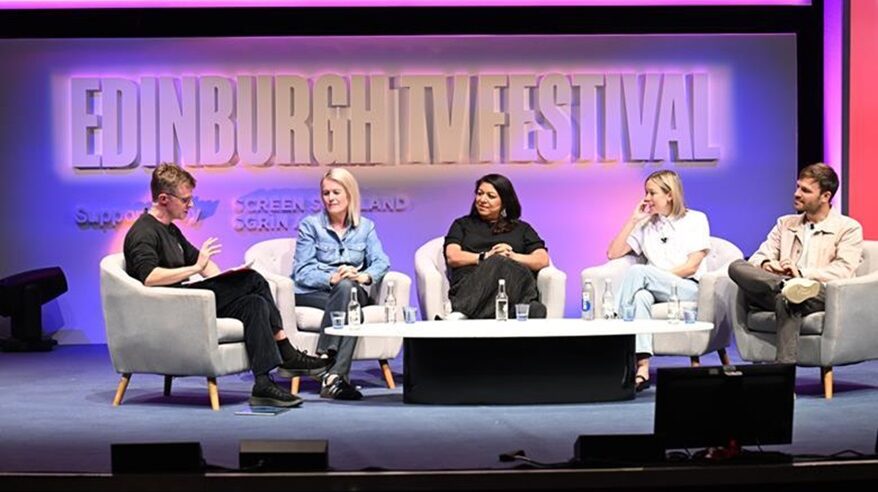 Panel of TV executives seated in a discussion with Edinburgh TV Festival logo on screen behind