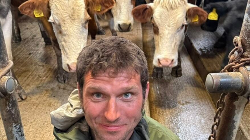 Presenter Guy Martin in close-up selfie in front of three white and brown dairy cows