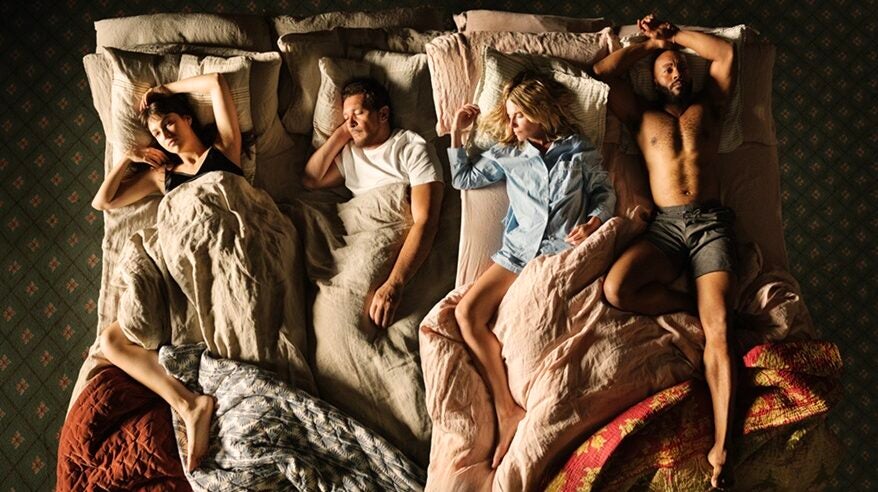 Two men and two women asleep in a rumpled bed