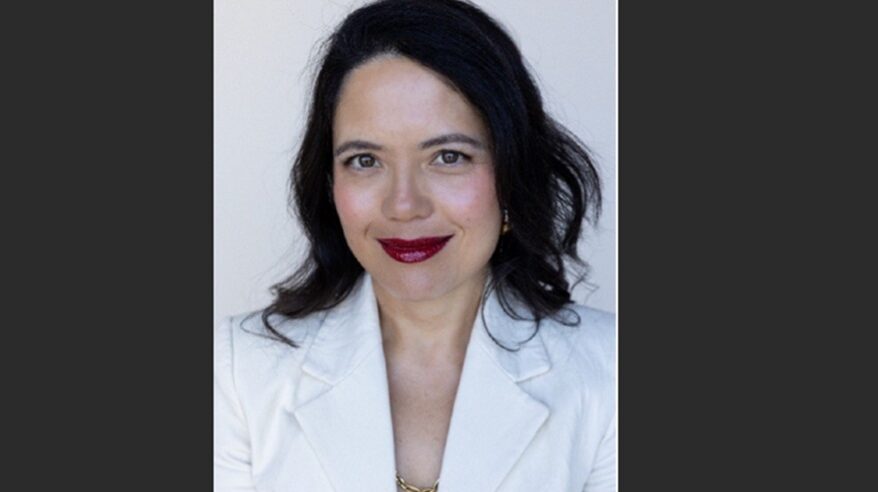 Headshot of producer Sarah Brocklehurst, in white tailored jacket against pale background