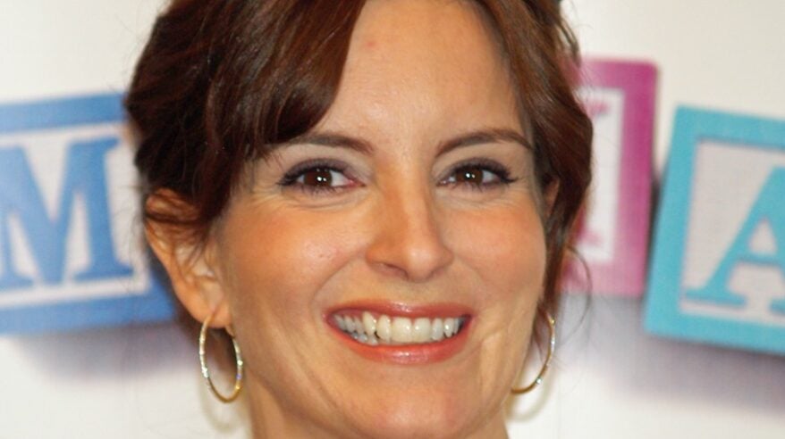 Woman with dark brown hair and gold hoop earrings, smiling at camera