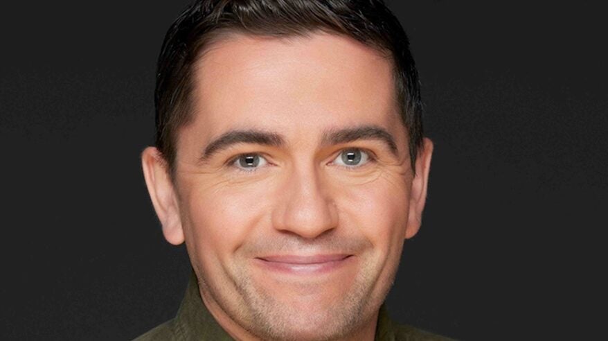 Headshot of TV exec Tom McDonald in dark shirt against dark background