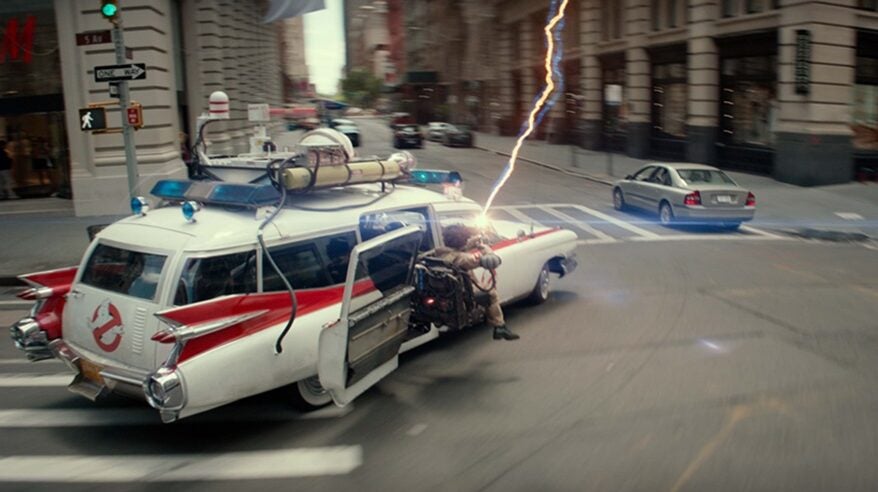 A still from Ghostbusters: Frozen Empire with the Ecto-1 car racing through NYC