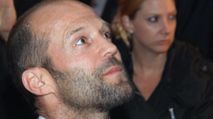 Actor Jason Statham with heavy stubble, looking upwards