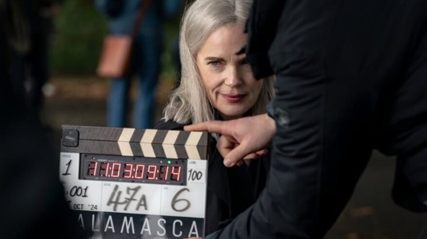 A grey-haired lady looks out ahead, with a clapperboard in front of her, for the start of shooting on Talamasca