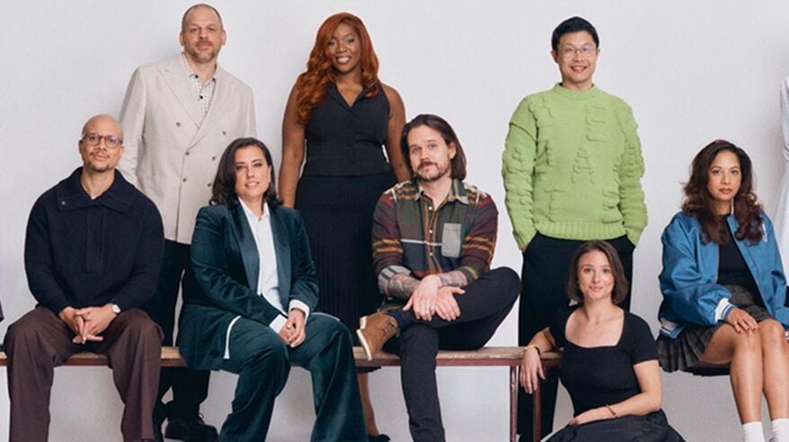 A group of young people, some seated on a bench and some standing, in a studio shoot