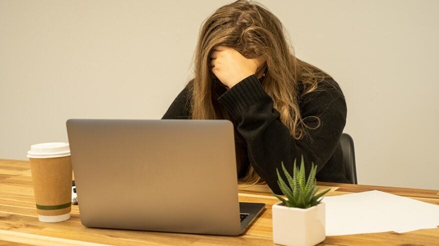 Woman at a desk with her head in her hands