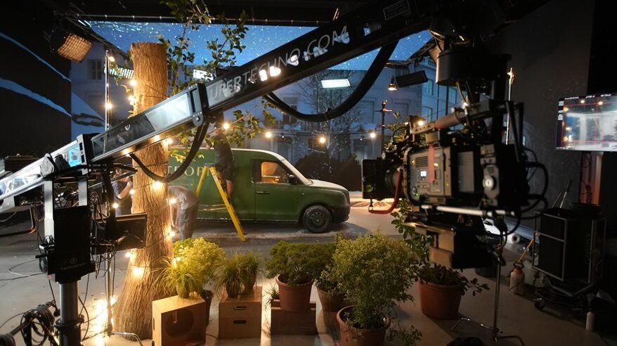 A vintage green car in a virtual production studio, with lots of camera equipment and lights